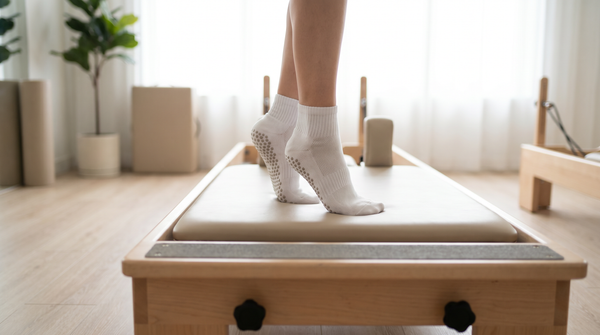 Woman wearing grip socks on a reformer pilates machine in a bright modern studio