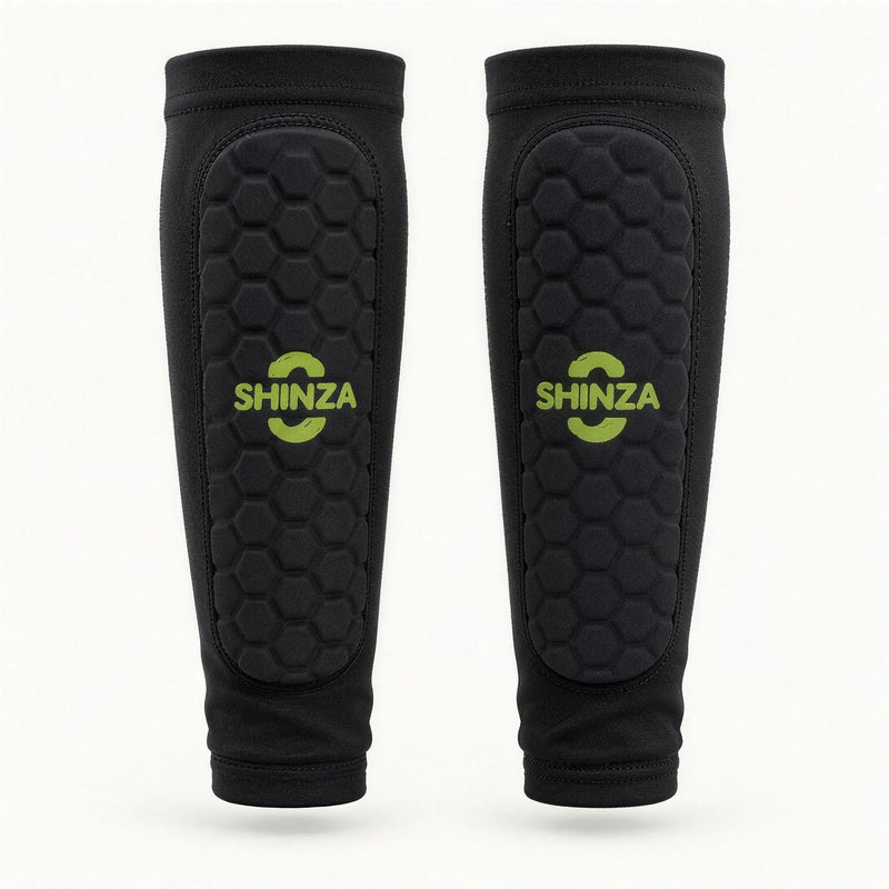 Pair of Shinza black football shin pad compression sleeves with hexagonal padded panel and printed lime green Shinza logo, front view on white background